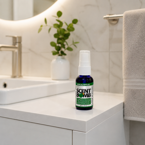 Scent Bomb bottle on a bathroom counter with a mirror and towel in the background