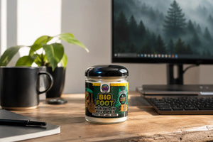 Front view of Big Foot candle by The Modest Co sitting on a wooden desk in home office with computer.