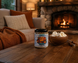 Front view of Toasted candle by The Modest Co sitting on a table in cozy living room with fireplace in the background