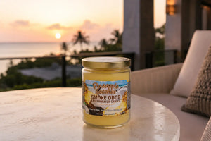 Pineapple Coconut odor eliminating candle sitting on table on hotel balcony with ocean and sunset in background