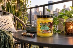 Wunderlust Smoke Odor Candle on table of city apartment balcony with skyline in background and ashtray nearby