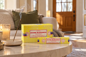 Divine Blessings Satya Incense sitting on white coffee table cozy, minimalist living room with green accents. 