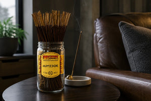 Humidor Wild berry Incense on dark wood coffee table next to brown leather couch in masculine style living room